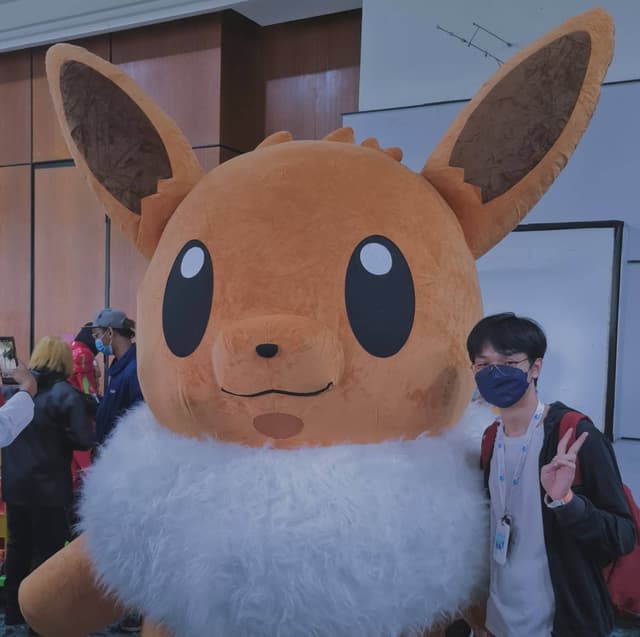 An image of Zach Khong taking a picture with a live size eevee plush